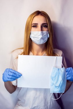 Yüzünde maske olan bir kızın elinde Covid19 işareti var. Beyaz arka plandaki bir kızın elindeki tablet. Elinde beyaz bir masa olan bir sarışın. Covid 19 yok. Elinde pankartla bir hemşire..