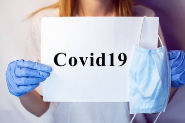 Yüzünde maske olan bir kızın elinde Covid19 işareti var. Beyaz arka plandaki bir kızın elindeki tablet. Elinde beyaz bir masa olan bir sarışın. Covid 19 yok. Elinde pankartla bir hemşire..