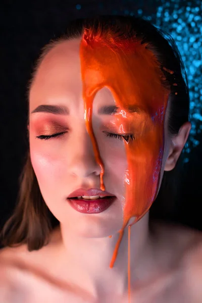 Young woman in paint. liquid paint flowing over a beautiful face and Body. Color portrait of Girl in Paint