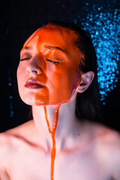 Young woman in paint. liquid paint flowing over a beautiful face and Body. Color portrait of Girl in Paint