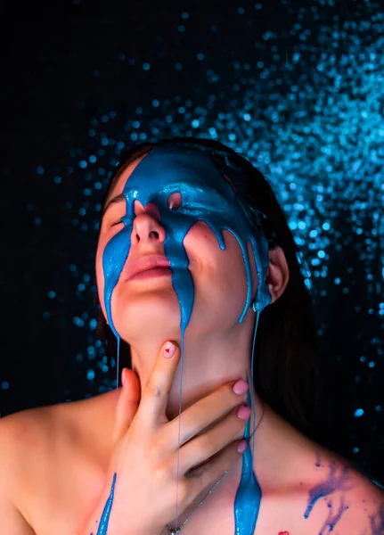 Young woman in paint. liquid paint flowing over a beautiful face and Body. Color portrait of Girl in Paint