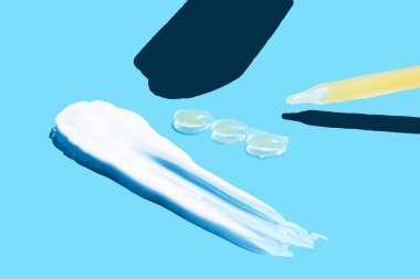 Mavi arka planda bir doz sıvı hyaluronik asit olan bir boru. Kozmetik konsepti. Düz yat. Tex için yer