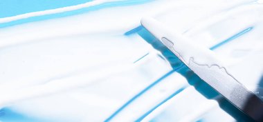 Mavi arka planda beyaz kozmetik kremi çapraz vuruşları. Yüz kremi, vücut losyonu, nemlendirici leke. Güzellik ürünü dokusu