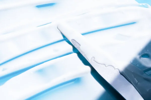 青の背景に白い化粧品クリーム斜線ストローク フェイスクリーム ボディローション 保湿剤スマッジ 美容製品の質感 — ストック写真