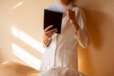 Kafkasyalı genç bir fizyoterapist müşterileri masaj prosedürü için not alıyor. Müşterileri masaj için kaydediyor. İşteki bir masör elinde bir not defteri tutuyor.