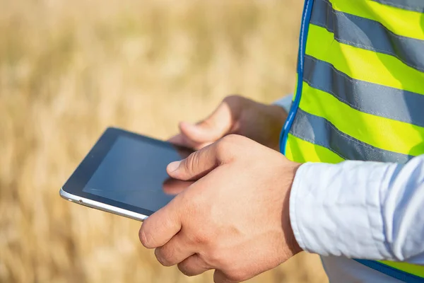 Hands of an engineer close-up, holding a tablet in his hands, close-up of male hands holding a tablet, agronomist engineer in the field, close-up of male hands