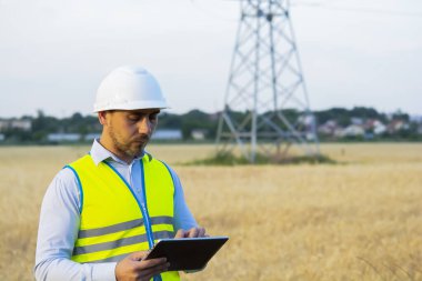 Bir elektrik mühendisi çalışıyor. Telefonda konuşmak ve tablet üzerinde çalışmak. Elektrik ağları denetleniyor.