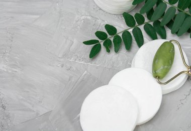 Cotton pads for makeup and white cotton swab green leaves, gray concrete background, nature spa concept, top view, fatlay, for copy space or product display