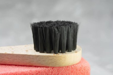 Brush for dry massage of the body, yellow and pink penza for the feet, cotton pads for the face, a green branch on a gray concrete background