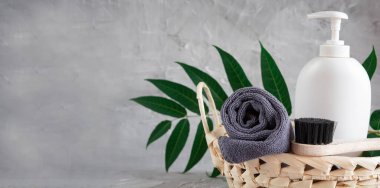 Gray towel, body massage brush, black bristle brush, foot penza, green ailanthus branch on gray background, bath accessories concept, bath products
