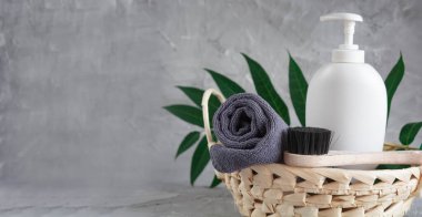 Gray towel, body massage brush, black bristle brush, foot penza, green ailanthus branch on gray background, bath accessories concept, bath products