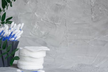 Cotton pads on a gray background, a green branch of a plant on a gray background, the concept of skin cleansing, cosmetics, eco cosmetics, skin care