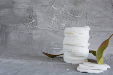 Cotton pads on a gray background, a red flower on a gray background, the concept of skin cleansing, cosmetics, eco cosmetics, skin care