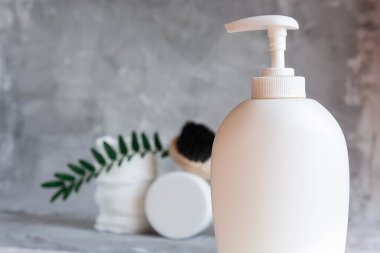 Care cosmetics on a gray background, a white jar of hair balm, a white jar of face cream, a black tube of lip balm, white cotton pads for removing makeup on a light gray background