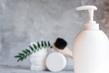 Care cosmetics on a gray background, a white jar of hair balm, a white jar of face cream, a black tube of lip balm, white cotton pads for removing makeup on a light gray background