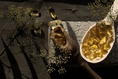 Masada ahşap kaplar, kaşıklar, çatallar, yiyecek için kepçeler, omega 3 vitaminler tahta kaşıkta yatıyor, spor, vitaminler, sağlıklı yaşam tarzı, beslenme malzemeleri, vitamin terapisi, spor malzemeleri