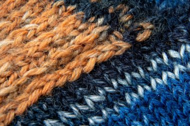 Knitted fabric from a combined colored yarn close-up full frame. Selective focus in the foreground.