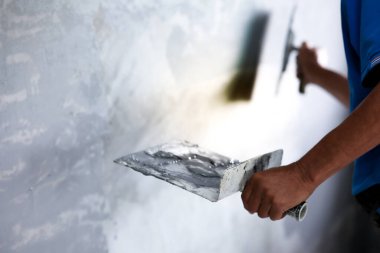 Boyacı duvarı dikdörtgen malayla boyuyor..