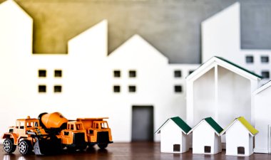 Minyatür ev modelleri ve ahşap masa üzerinde küre sikke olan inşaat kamyonu modelleri. Gayrimenkul geliştirme ya da gayrimenkul yatırımı. İnşaat endüstrisi iş konsepti.