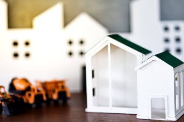 Minyatür ev modelleri ve ahşap masa üzerinde küre sikke olan inşaat kamyonu modelleri. Gayrimenkul geliştirme ya da gayrimenkul yatırımı. İnşaat endüstrisi iş konsepti.