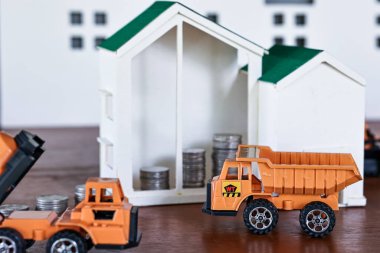 Minyatür ev modelleri ve ahşap masa üzerinde küre sikke olan inşaat kamyonu modelleri. Gayrimenkul geliştirme ya da gayrimenkul yatırımı. İnşaat endüstrisi iş konsepti.