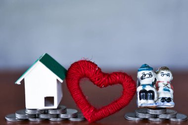 Minyatür ev, eğitim sertifikası, kalp ve oyuncak modelleri sarı arka planda para istifleme üzerine. Para biriktirme kavramı.