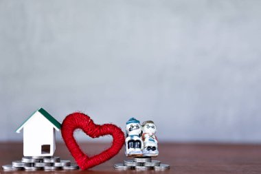 Minyatür ev, eğitim sertifikası, kalp ve oyuncak modelleri sarı arka planda para istifleme üzerine. Para biriktirme kavramı.