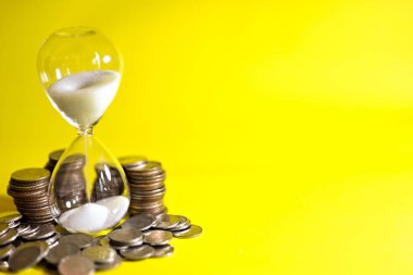 Kum saati ve bozuk para yığınının içinde akan kum. İş bitiş tarihi kavramı için geri sayım zamanlayıcısı.