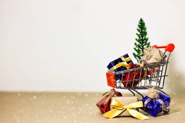 Mutlu Noeller, mutlu yıllar ve boks günü konsepti. Mevcut kutular, alışveriş arabası, çam ağacı ve açık kahverengi arka planda ev modelleri..