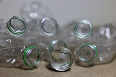 Plastik kirliliği. Boş plastik şişe, plastik torba ve masada kum saatinin içinden geçen Wolrd marka kristal bardak. Küresel warimg konsepti için geri sayım zamanlayıcısı.