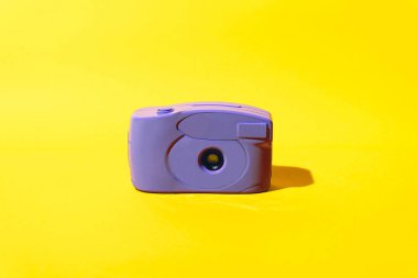 Sarı arka planı ve küçük mercek açıklığı olan eski bir kameranın çok peri rengi.