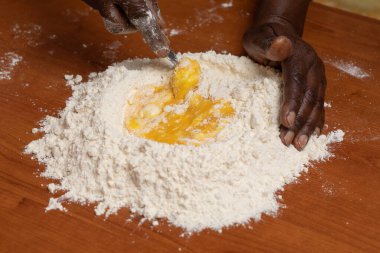 Siyah Afrikalı elleri mutfak masasında yumurta ve un karıştırır. Yemeği içeride hazırlar.
