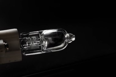 Makro görünümü düz kenarlı elektrik ampulü dikey konumda fotokopi alanı ile siyah arkaplana karşı kapalı.