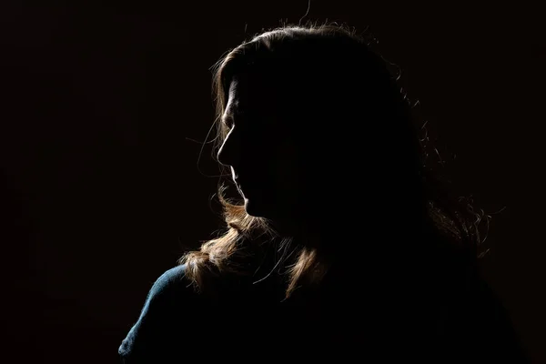 Half face of unrecognizable woman portrait in shadow shrouded in darkness isolated on black background with wide copy space, concept of anonymity to hide identity