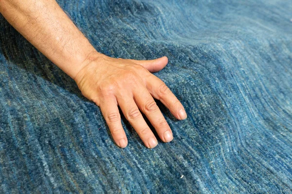 expert hand of craftsman who tests the softness of a fine carpet, the value concept of a hand-woven carpet