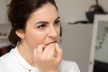 Portrait of a girl biting her nails in a compulsive way. Onicophagia is a psychological disorder in which the patient eats nails and the cuticles of the fingers of the hands