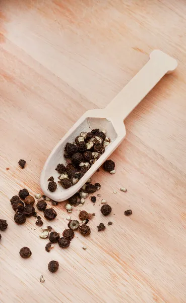 black peppercorns on wooden surface
