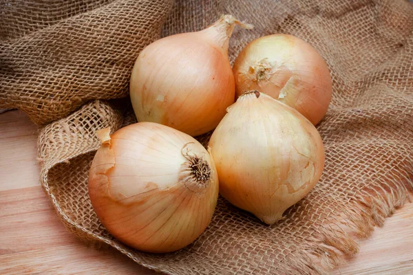Çuval bezi ve çiftlik masasında kahverengi soğan