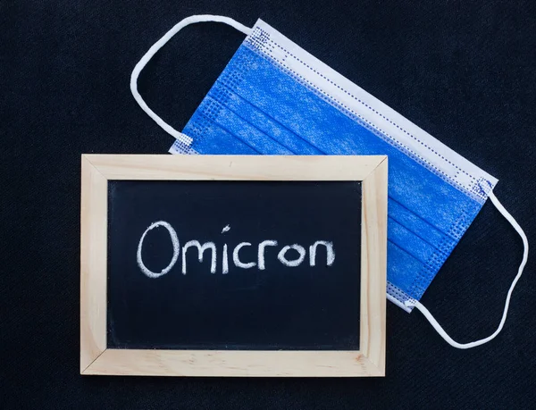 maske ve Omicron siyah arkaplanda karatahtaya yazılmış