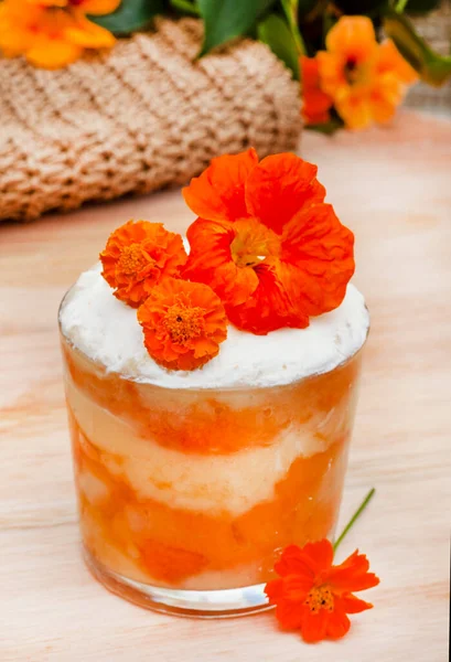 Orange peach and custard trifle serving with bright orange flowers
