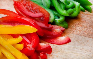 Taze üç renkli dolma biber. Tahta yüzeyde kesilmiş jülyen.