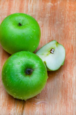 Tahta yüzeyde su damlacıklarıyla taze ve çıtır çıtır yeşil büyükanne demirci elmaları