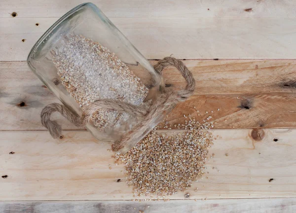 steel cut oats spilling out of almost empty jar on rustic wooden table