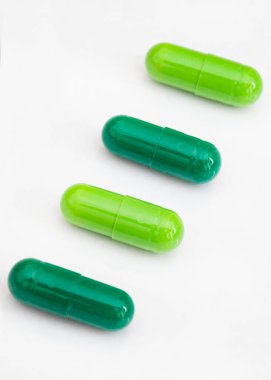 Beyaz arkaplanda yeşil ilaç kapsülleri