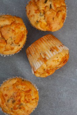 Peynir ve bitkisel, lezzetli kekler, puantiyeli gri bir yüzey üzerinde peynirle pişirilmiş.