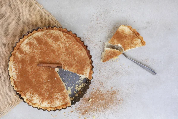 Traditional South African milk tart freshly baked and in tin. Mottled grey and rustic surface with copy space