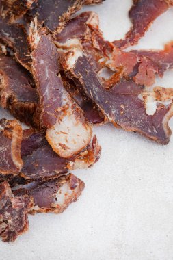 Güney Afrika Biltong 'u, kurutulmuş ve kurutulmuş et dilimlenmiş ve arka planda fotokopi alanı olan gri bir yer.