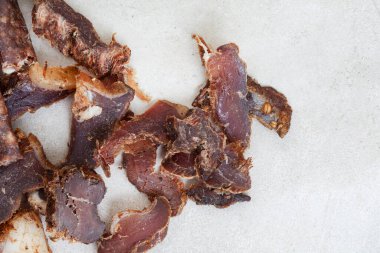 Güney Afrika Biltong 'u, kurutulmuş ve kurutulmuş et dilimlenmiş ve arka planda fotokopi alanı olan gri bir yer.