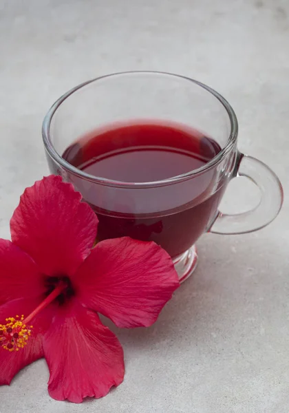 Bright and flavorful hibiscus tea in a glass cup, with hibiscus flower and copy space