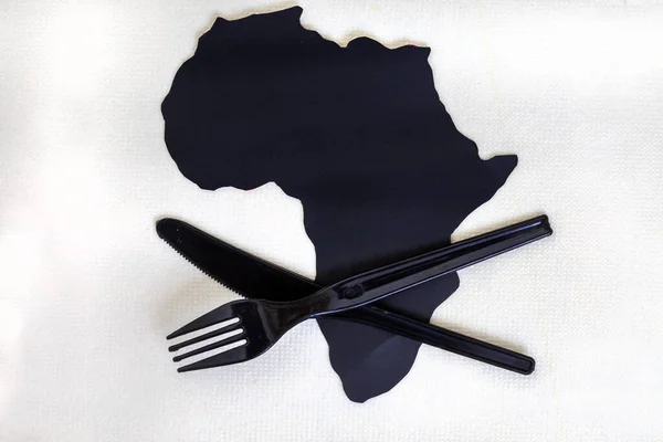 black cut out of Africa continent on white with plastic cutlery and copy space